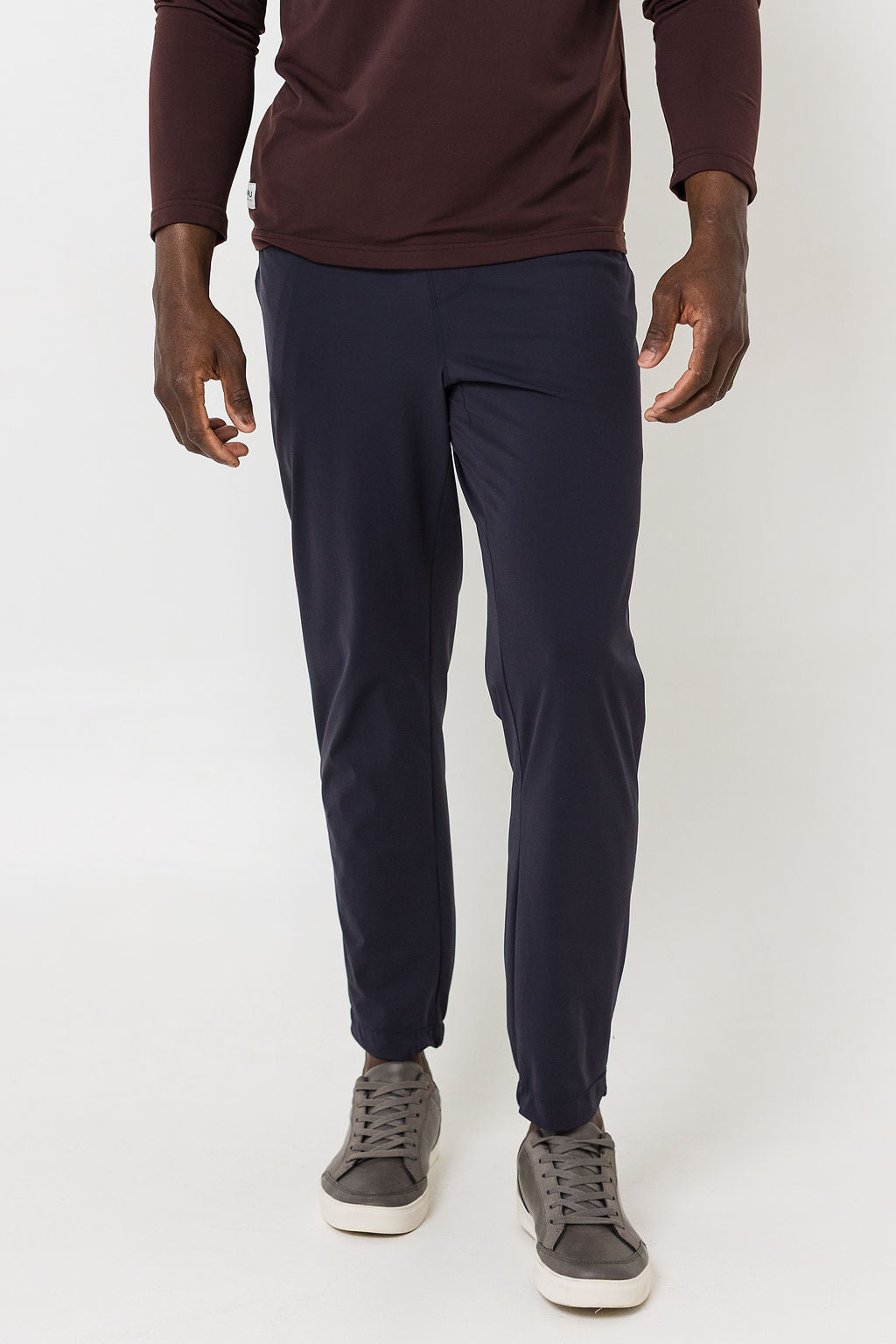 Person wearing navy jogger pants and maroon long-sleeve shirt on a white background