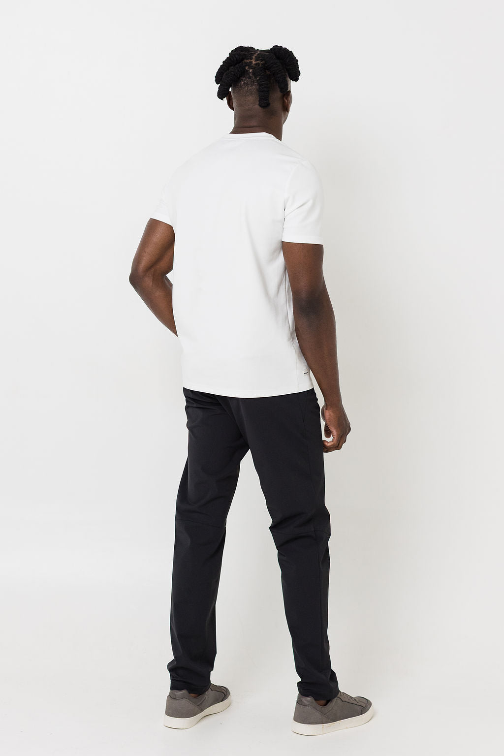 Person wearing a white t-shirt and black pants on a white background