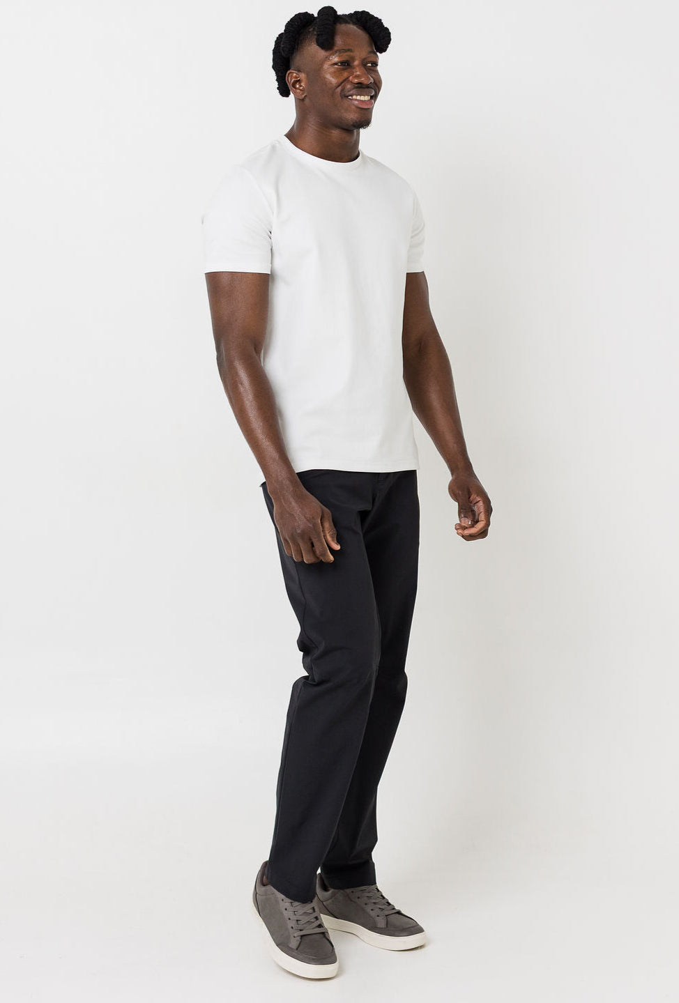 Man wearing a white t-shirt, black pants, and gray sneakers on a white background
