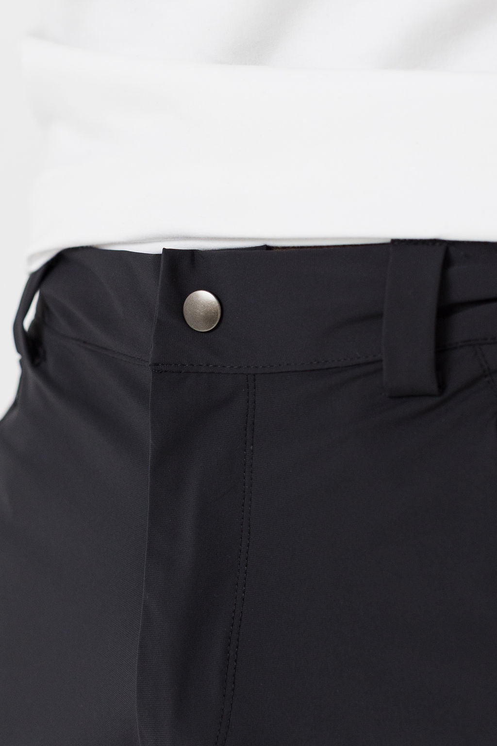 Close-up of black pants with a button on a white background