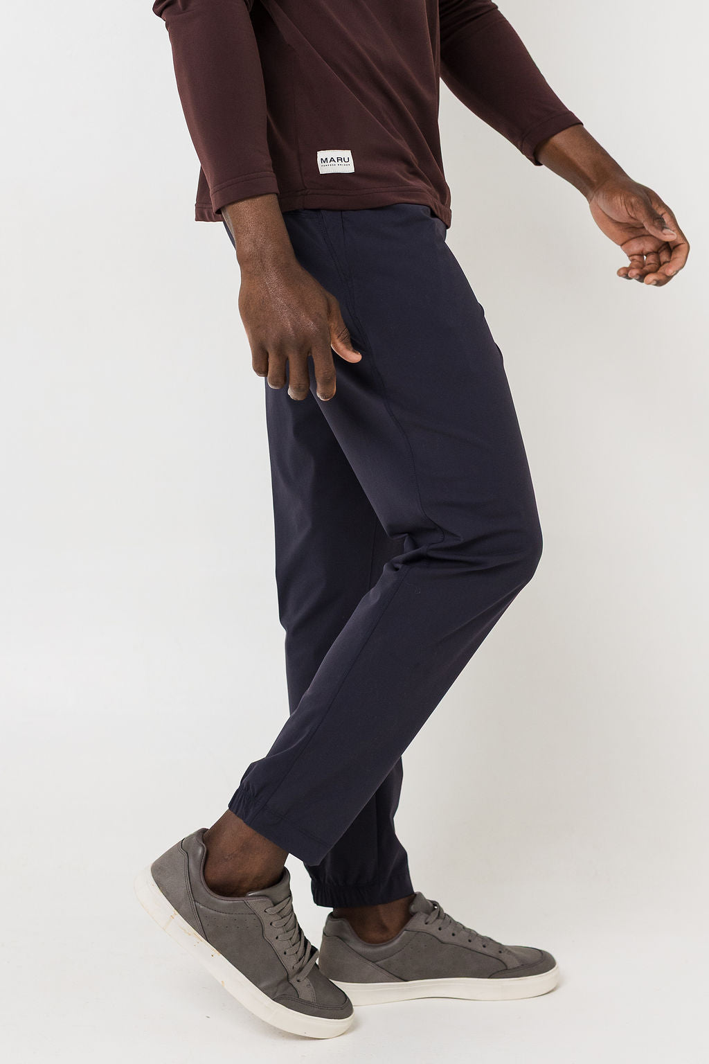 Person wearing navy pants and gray shoes on a white background